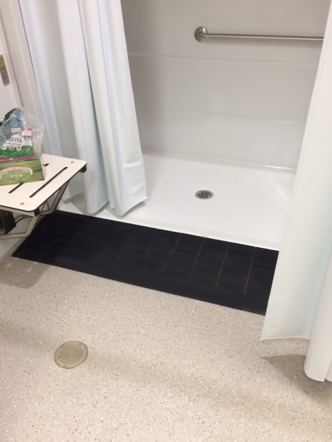 ADA compliant shower ramp providing safe roll in shower access for elderly and disabled users, and to help caregivers